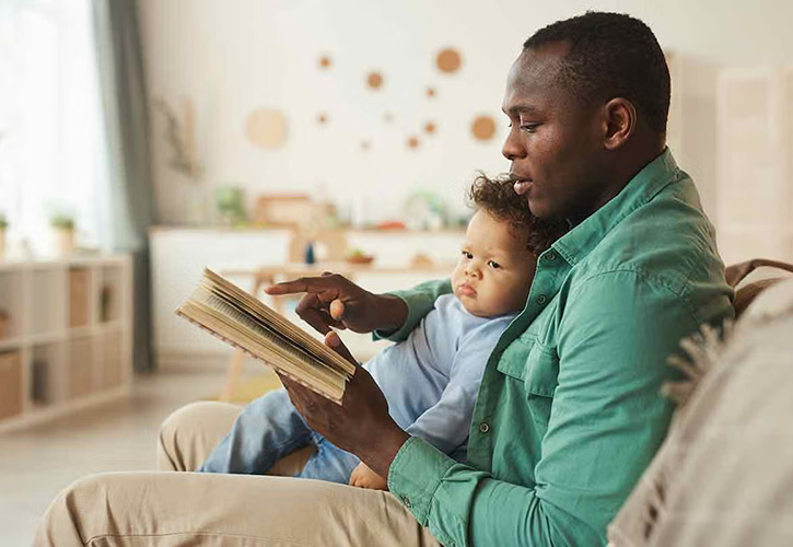 Father sitting on chair reading to child