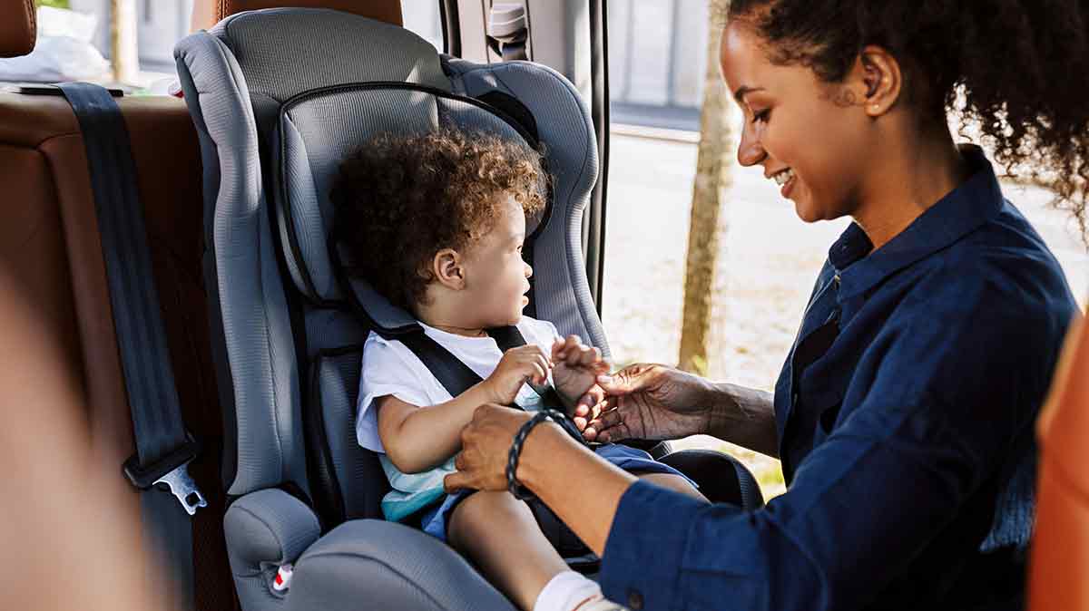 mom putting child into car seat safely