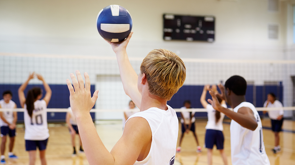 High school player serving a volleyball