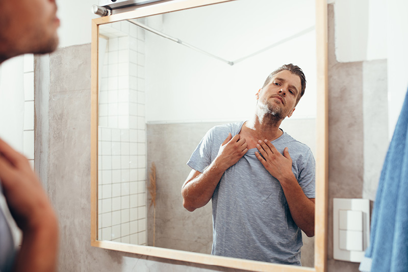 Man examining his skin in the mirror
