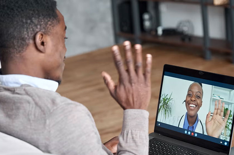 man waving to doctor using computer for virtual visit